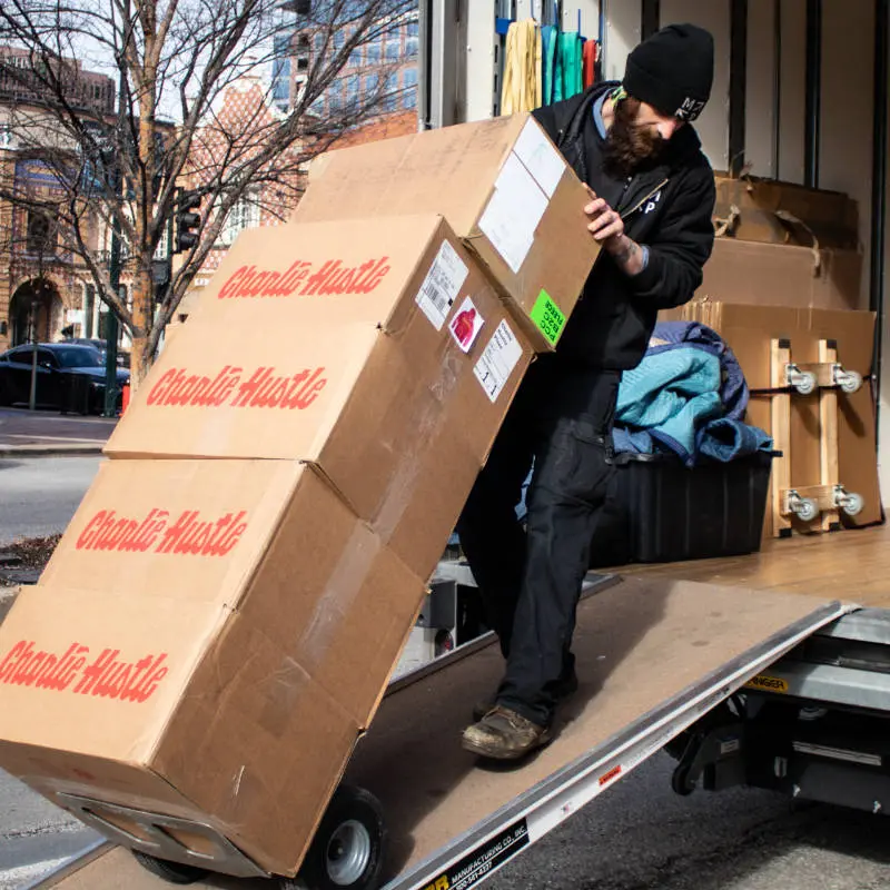 Mover loading large boxes onto a truck using a dolly.